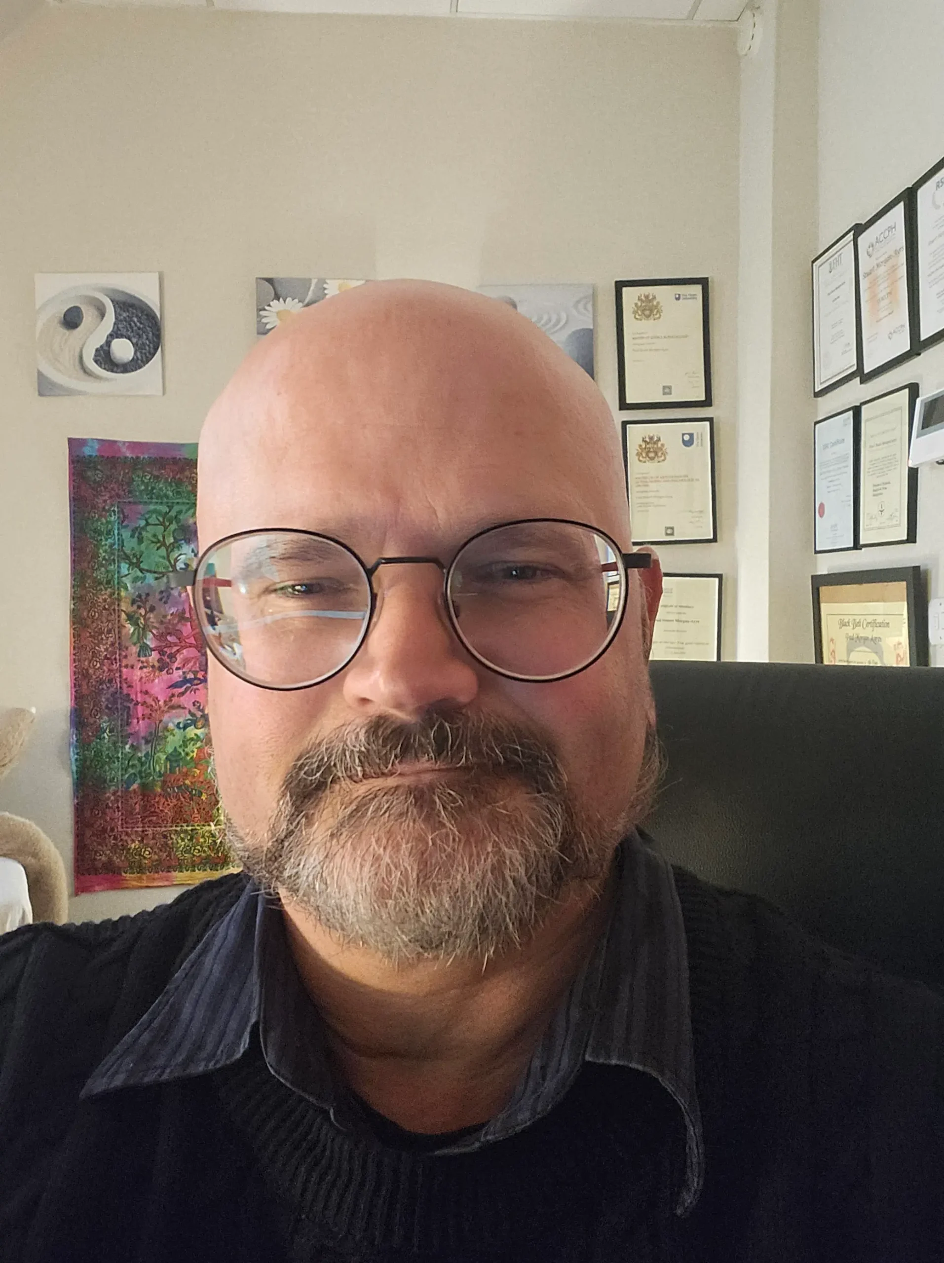 Portrait of Stuart Morgan-Ayrs with framed certificates on the wall behind him.